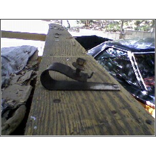 1972 Ford Ranchero - A close-up of a metal clamp secured to a wooden surface, with a vehicle partially visible behind it.