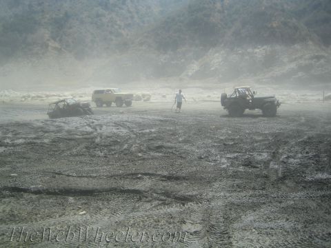 1987 Suzuki Samurai - Multiple off-road vehicles are seen in a dusty, outdoor environment with hills in the background.
