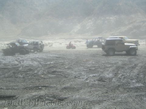 1987 Suzuki Samurai - Multiple off-road vehicles are gathered in a dusty, open area with hills in the distance.