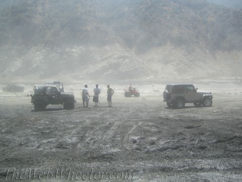 1987 Suzuki Samurai - Several off-road vehicles are parked in a dusty, barren landscape with hills in the background.