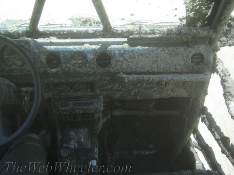 1987 Suzuki Samurai - The interior of a 1987 Suzuki Samurai is heavily caked in mud, obscuring most details.