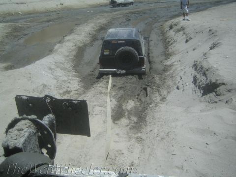 1987 Suzuki Samurai - A black 1987 Suzuki Samurai is being pulled from a deep sandy track, with another vehicle visible in the background.