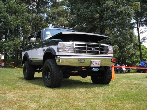 1994 Ford Bronco - A two-tone green and white Ford Bronco is displayed with its hood open at an outdoor event.