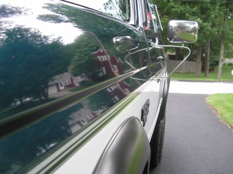 1994 Ford Bronco - Side profile of a 1994 Ford Bronco, its two-tone green and white paint scheme and chrome side mirror.