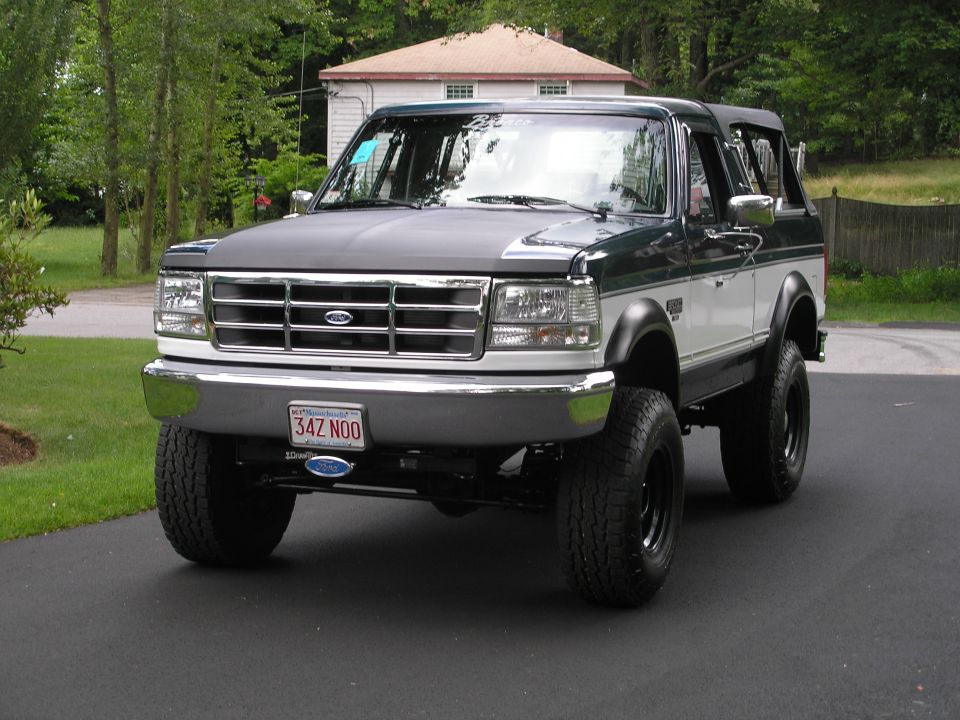 Lifted Ford Bronco with aftermarket grille and hood, parked on a driveway