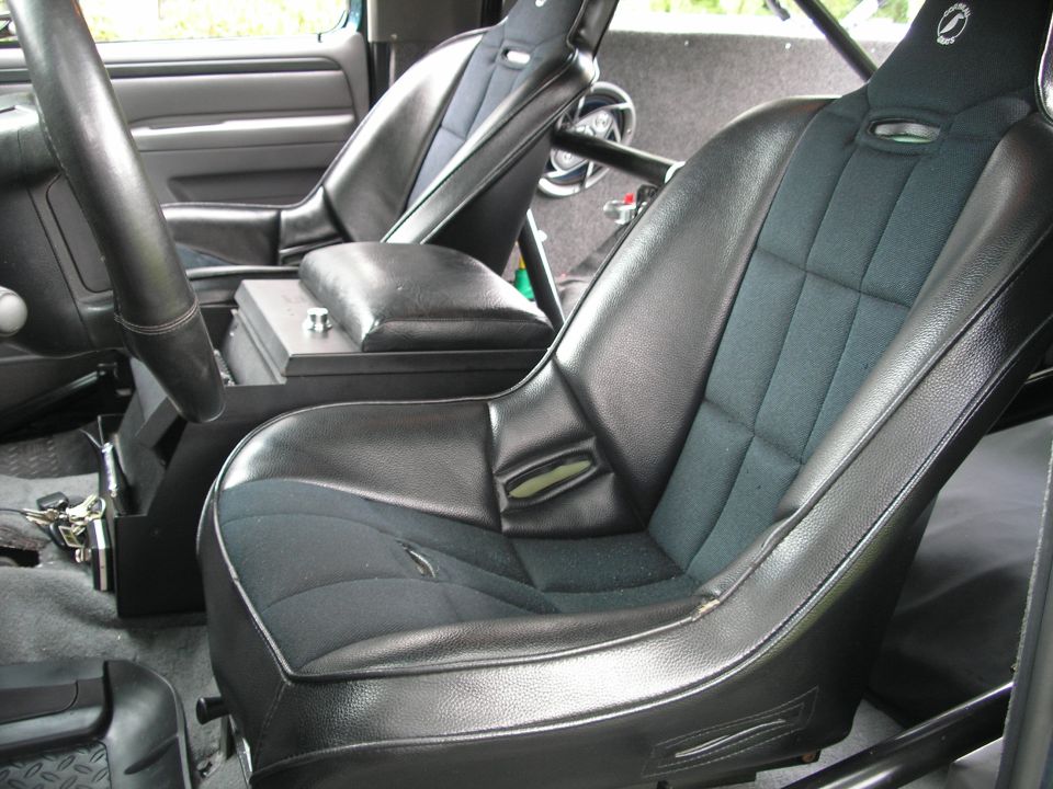 Interior view of a vehicle with racing seats, a roll cage, and a center console