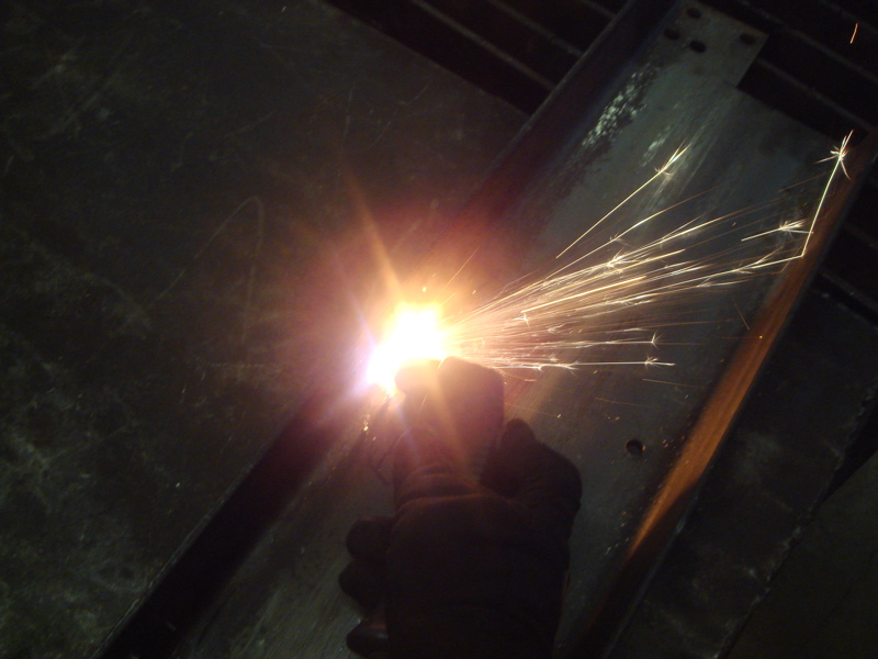 welder's gloved hand creating bright sparks while working on metal