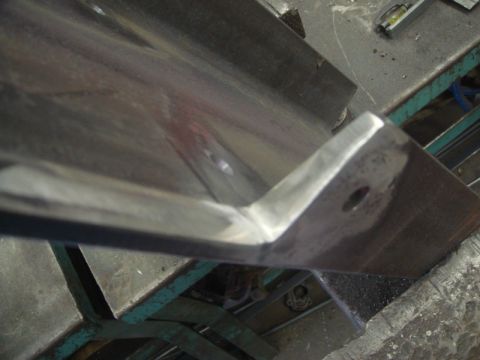 1996 Ford Bronco - Metal bracket with a hole, likely for mounting or attachment, on a work surface.