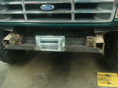 1996 Ford Bronco - A winch is mounted to a custom metal bumper on the front of a Ford truck.