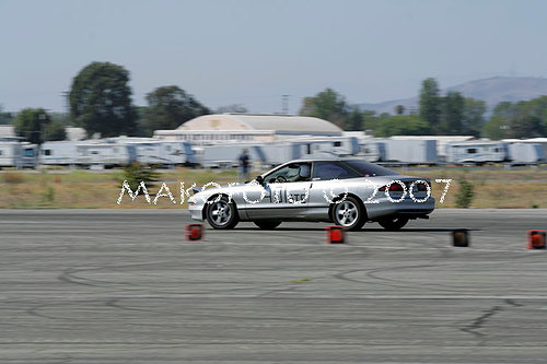 Silver 1993 Ford Probe driving on a race track with orange cones