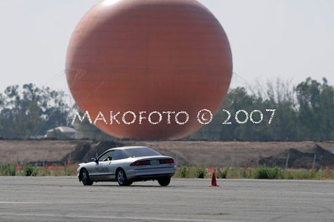 1993 Ford Probe - A silver coupe is seen on a paved surface with a large orange sphere dominating the sky behind it.