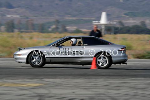 1993 Ford Probe - A silver 1993 Ford Probe races on a track, marked with numbers and surrounded by cones.