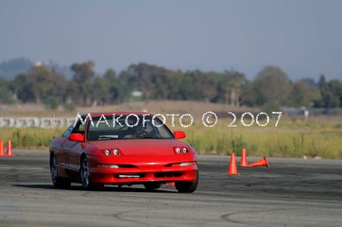 1993 Ford Probe - A red sports coupe navigates a course marked by orange cones on a sunny day.
