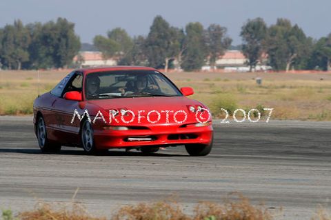 1993 Ford Probe - A red 1993 Ford Probe is captured in motion on a race track during an autocross event.