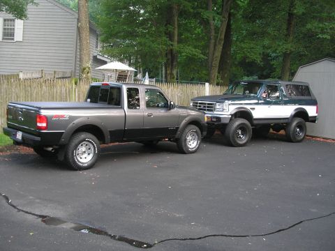 1994 Ford Bronco - A lifted 1994 Ford Bronco is parked next to a gray pickup truck in a driveway.