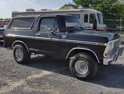1978 Ford Bronco - A black 1978 Ford Bronco is parked on a gravel lot, showing its distinctive body style and chrome accents.