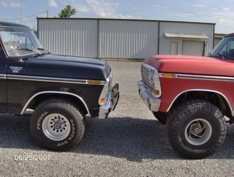 1978 Ford Bronco - Two classic Ford Broncos are parked facing each other in front of a metal building.