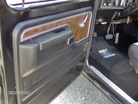 1978 Ford Bronco - Interior view of a 1978 Ford Bronco, showing the door panel and a "Built Ford Tough" floor mat.