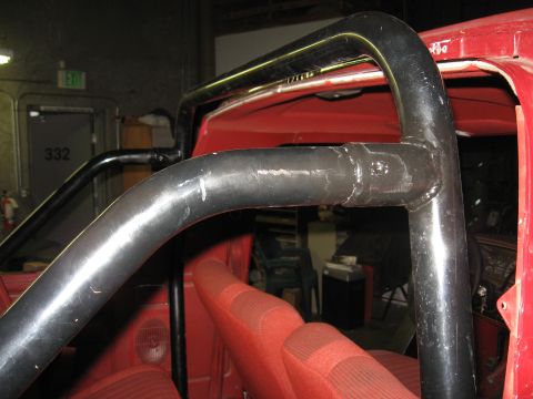 1991 Ford Bronco - Close-up view of a roll bar installed inside a red vehicle, showing the interior and seats.