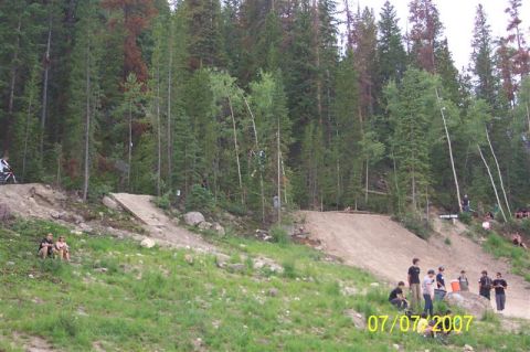 1978 Ford Bronco - A mountain bike jump course is set up on a wooded hillside with spectators watching.