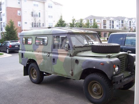 1974 Land Rover Land Rover - This camouflaged Land Rover Defender 110 is seen from the side with a spare tire mounted on the hood.