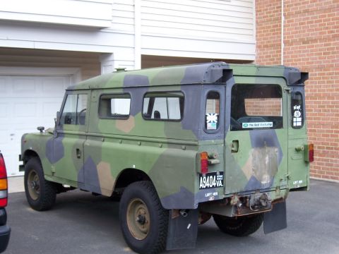 1974 Land Rover Land Rover - This Land Rover Defender 110, painted in camouflage, is viewed from the rear quarter, parked outdoors.