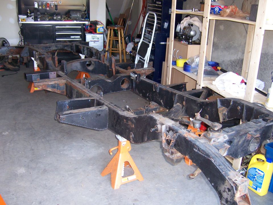 Stripped black Land Rover chassis frame on orange jack stands in a garage workshop