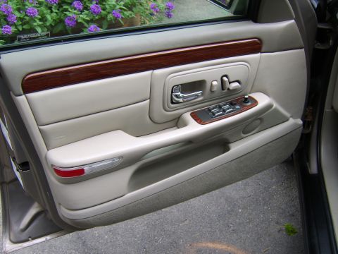 1996 Mercury Grand Marquis - The interior door panel features light-colored upholstery, wood accents, and chrome hardware.