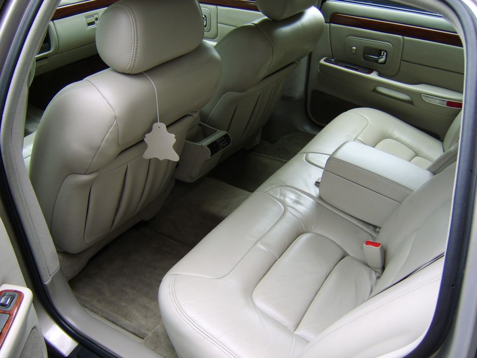 Tan leather rear seat interior of a sedan with wood-trim door panel
