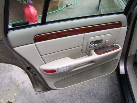 1996 Mercury Grand Marquis - The interior door panel of a 1996 Mercury Grand Marquis features wood trim accents and beige upholstery.
