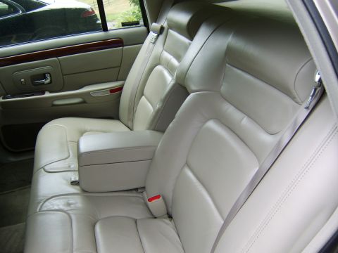 1996 Mercury Grand Marquis - The interior of a car shows tan leather seats and wood trim on the door panel.