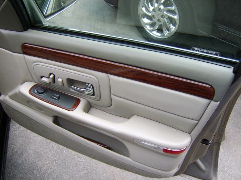 1996 Mercury Grand Marquis - Close-up of a car's interior door panel, wood grain trim and polished metal accents.