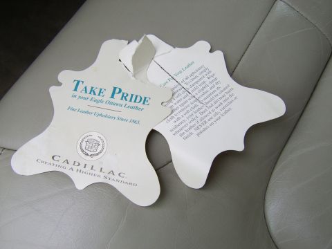 1996 Mercury Grand Marquis - Two Cadillac leather care tags are placed on a car's interior seat.