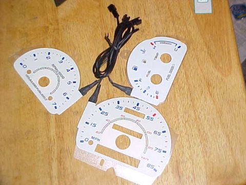 1995 Ford Taurus - Set of white gauge faces with blue markings, including MPH, km/h, and RPM scales, along with fuel and temperature indicators.