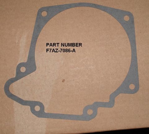 1999 Ford Crown Victoria - A gray paper transmission extension housing gasket laid flat on cardboard, with six bolt holes around its irregular outline. Overlaid text…
