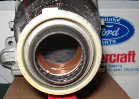 1999 Ford Crown Victoria - End-on view into the tail of an aluminum transmission extension housing, showing the output shaft seal with its light tan outer casing and…
