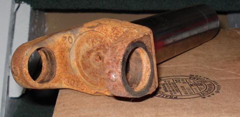 1999 Ford Crown Victoria - A surface-rusted driveshaft slip yoke resting on cardboard inside a box, shown from the U-joint end with both bearing cap bores facing the…