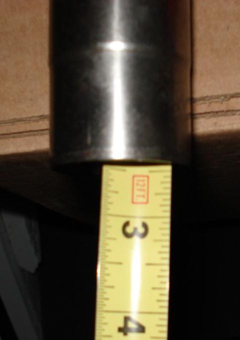 1999 Ford Crown Victoria - Close-up of a polished steel driveshaft slip yoke tube laid on cardboard with a yellow tape measure held alongside it, the markings between…