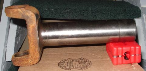 1999 Ford Crown Victoria - Side profile of a driveshaft slip yoke lying on cardboard against green carpet, showing the polished steel splined shank and the heavily ru…