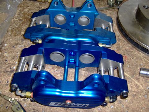 1978 Ford Bronco - Two blue brake calipers and a brake rotor are laid out on a workbench, suggesting a repair or upgrade.
