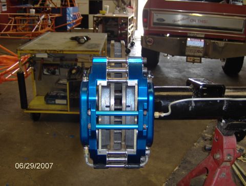 1978 Ford Bronco - A blue brake caliper is mounted on a rear axle, with a red Ford truck visible in the background.