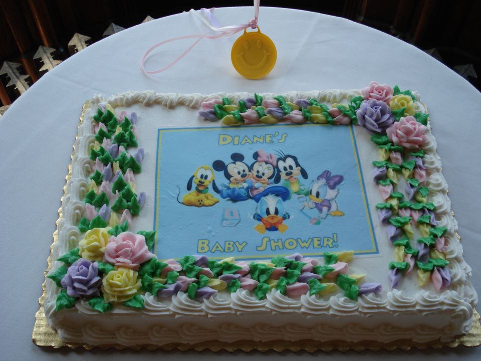Rectangular cake decorated with Disney characters and flowers, reading 'DIANE'S BABY SHOWER!'