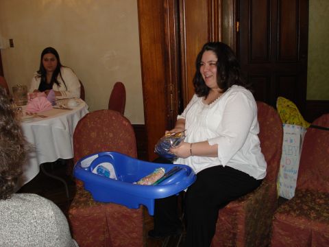 2000 Ford Crown Victoria - A woman smiles while opening gifts at a baby shower, with a blue baby bathtub and gift bags visible.