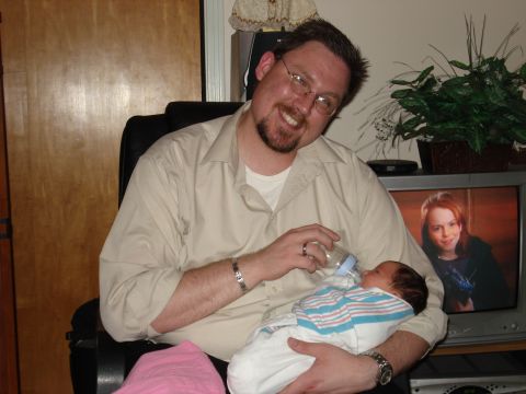 2000 Ford Crown Victoria - A man smiles while feeding a newborn baby from a bottle.