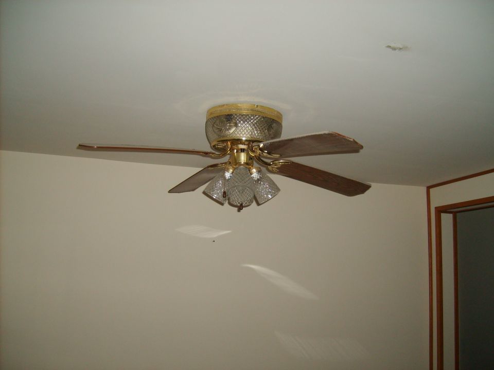 Ceiling fan with wooden blades and gold accents.