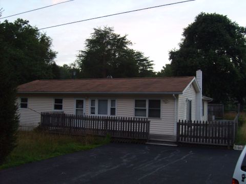 2004 Ford Crown Victoria - A single-story house with a brown roof and white siding is shown on a cloudy day.