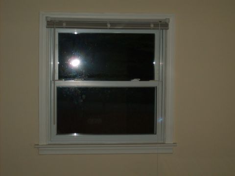 2004 Ford Crown Victoria - A closed window with blinds is shown, with a bright reflection visible in the glass.