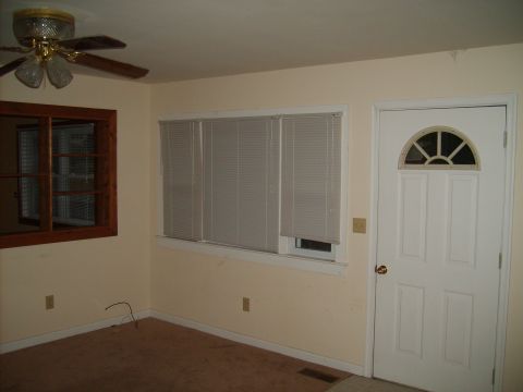 2004 Ford Crown Victoria - This is an interior scene of a room, a ceiling fan, a window with blinds, and a white door with a decorative glass panel.