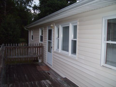 2004 Ford Crown Victoria - A house exterior shows a wooden deck, railing, door, and windows under a cloudy sky.
