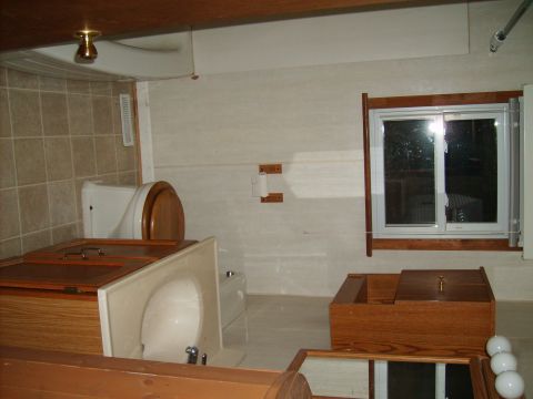 2004 Ford Crown Victoria - Interior scene of a bathroom with tiled walls, a toilet, a sink, and wooden cabinetry. A window is visible on the right wall.